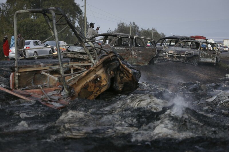 epaselect epa05670186 A man takes a photograph of burnt out cars on the highway near Naivasha, some 80km north of the capital Nairobi, Kenya, 11 December 2016. An oil tanker lost control and rammed into cars and exploded, causing a huge fire on one of Kenya's main highways on late 10 December. Local newspaper reported 40 people were killed and 12 vehicles were burnt. EPA/DAI KUROKAWA